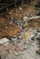 a small stream in the sikidang crater in dieng, banjarnegara that flows through a rocky and barren landscape. The rocks are of various sizes, and the ground is covered with layers of gravel and sand. photo