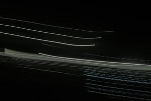 shows a long exposure photograph of light trails in the lamp. The trails are white and green, and they are streaking across the black background photo