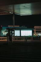 shows a view of a modern building at night, with a large window that is brightly lit. The building is located in an airport area, and the scene is quiet and peaceful. photo