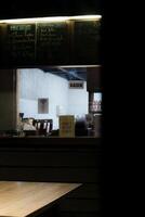 a closed coffee shop at night. The shop's menu is visible on the wall, and a Sorry, we are closed sign is displayed in the window. The interior of the shop is dimly lit, with a counter and a Kasir photo
