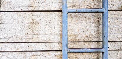 Gray steel ladder for climbing to rooftop on rough wall with line and copy space for background. Art wallpaper, Object and Shape photo