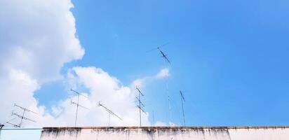 Many television antenna on rooftop of building with white cloud and blue sky with copy space. Technology, Communication and Art concept. photo