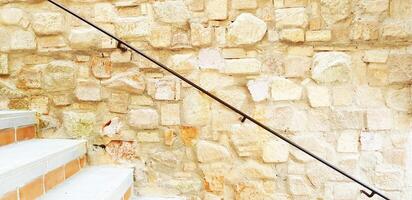 Concrete staircase and brown stainless steel railing big stone wall background with copy space. Interior or Exterior design, Wallpaper, Art and Pattern photo