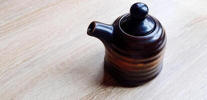 Black ceramic jug or mug tea putting on the wooden table with copy space. Sigle object, Dishware in Japan style,, Design and Container concept. photo