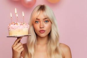 Blowing the birthday candles. Attractive young woman making a wish while holding a delicious cake on stick next to copy space. photo