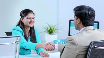 A happy young Indian woman rejoicing and shaking hands with an employee when was recruited during an interview in the office photo