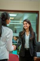 A happy young Indian woman rejoicing and shaking hands with an employee when was recruited during an interview in the office photo