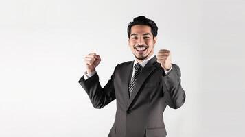 A happy young Indian businessman celebrates a victory with a joyful smile and raised fists in an office photo