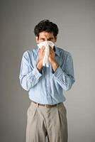 An Indian man covered his nose with tissue paper and he looked very stress on a grey background photo