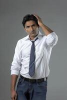 An Indian man lokking so sad andhand on his forehead against an isolated a grey background photo