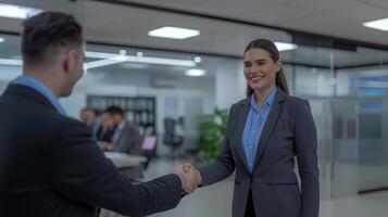 A young beautiful modern Indian woman rejoicing and shaking hand with an employee when was recruited during an interview in the office photo