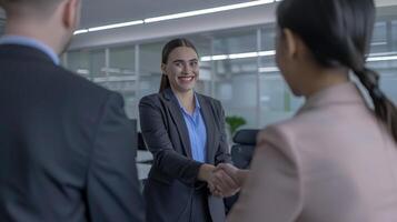 A young beautiful modern Indian woman rejoicing and shaking hand with an employee when was recruited during an interview in the office photo