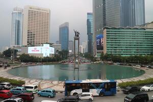 Busy city roundabout with fountain and tall buildings photo