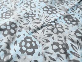 The fabric is patterned with a dense arrangement of blooming floral motifs in medium tones photo