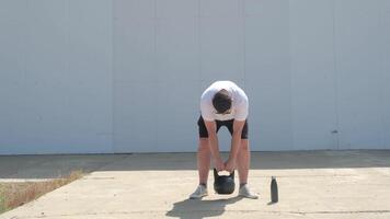 sports and leisure. strong Caucasian man working out using kettlebell in the park, white wall background video