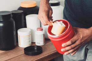 Hands holding scoop of creatine container with copy space healthy life. photo