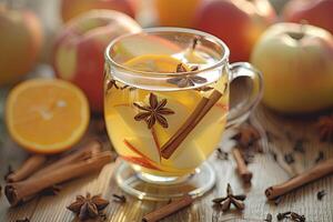 transparente vaso de caliente manzana sidra con piezas de manzanas y estrella anís. un de madera mesa decorado con maduro manzanas y naranjas transporta un acogedor otoño atmósfera foto