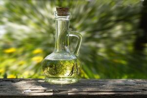 Jug filled with oil over blurred green grass background photo