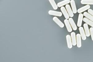 Capsule pills scattered on gray background photo