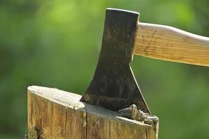 Closeup view of axe with a wooden handle embedded in a log of wood photo