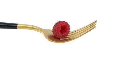 Ripe raspberry on a golden fork isolated on white background photo