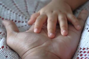 A childs gentle hand resting on an adults palm, displaying affection and trust photo