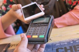 A customer making a contactless payment with a smartphone in a cafe using a mobile wallet photo