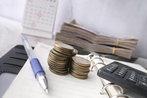 stack of coins, cash and calculator on notepad. photo