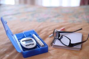 diabetic measurement tools and eyeglass on bed photo
