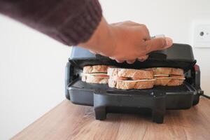 Hand using finger to press button on grill gadget photo