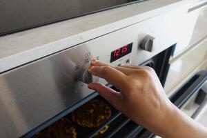 Close up of men hand setting temperature control on oven. photo