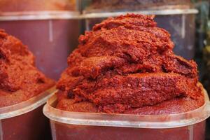 Observing the detailed view of containers filled with Red Pepper Paste available at a local market photo
