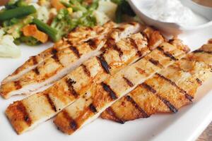 close up of grill chicken meat served with fresh vegetables on a plate photo