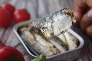 fork pick sardines from a open container photo