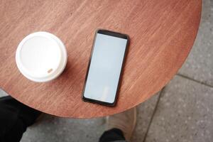 smart phone with empty screen and a coffee on table photo