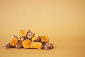 turmeric roots on a orange color background with copy space photo
