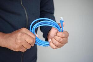 A closeup of hands holding a coiled blue Ethernet cable for a network connection photo