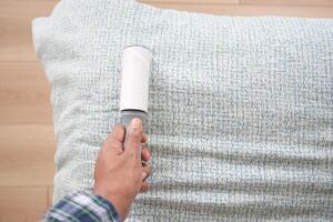 using an adhesive roller to remove lint and fluff from a bed . photo