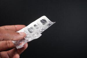 holding a empty pills of blister pack against black background photo