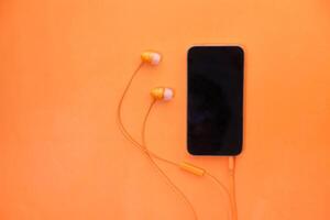 smart phone and earphone on orange background . photo