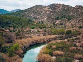 landscape of a river flowing in a mountainous area on a cloudy day photo