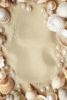 vertical border frame template of various shells and pearls on sand background top view with copy space photo