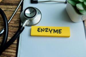 Concept of Enzyme write on sticky notes isolated on Wooden Table. photo