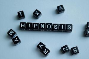 Concept of Hipnosis written on wooden blocks. Cross processed image on Wooden Background photo