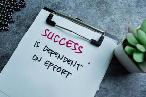 Concept of Success is Dependent on Effort write on paperwork isolated on wooden background. photo