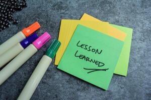 Concept of Lesson Learned write on sticky notes isolated on Wooden Table. photo