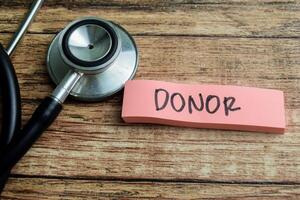 Concept of Donor write on sticky notes isolated on Wooden Table. photo
