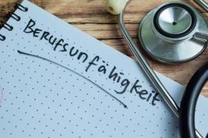 Concept of Learning language - German. Berufsunfahigkeit it means Occupational disability written on book. German language isolated on Wooden Table. photo