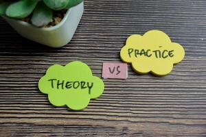 Concept of Practice vs Theory write on sticky notes isolated on Wooden Table. photo
