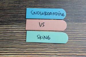 Concept of Snowboarding vs Skiing write on sticky notes isolated on Wooden Table. photo